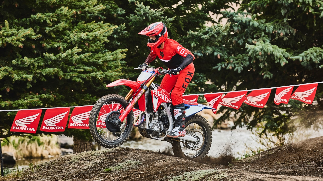 Motocross rider in red gear accelerating on a red dirt bike.