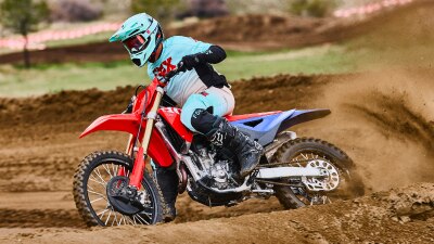 Rider on a blue and white dirt bike turning sharply on dirt.