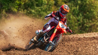 Motocross racer riding a red dirt bike on a track.