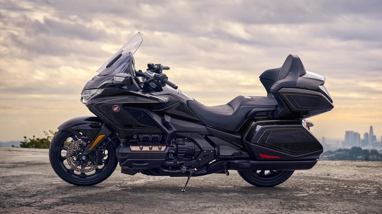 Profil latéral d'une moto de tourisme garée devant un paysage pittoresque.