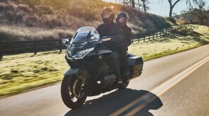 Deux personnes conduisant une moto de tourisme sur une route sinueuse.