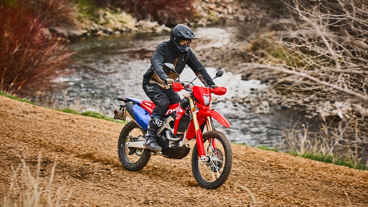 A rider navigating a dual sport motorcycle on a dirt path.
