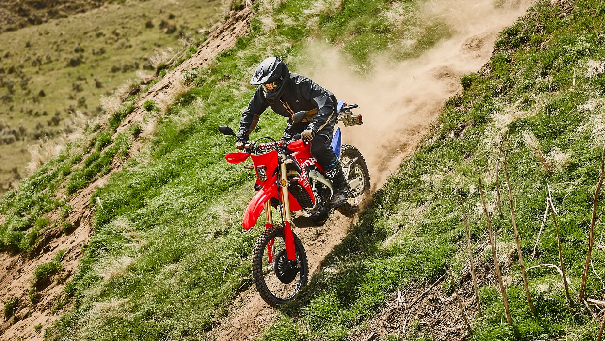 Un motard sur une moto double usage dans un environnement tout-terrain.