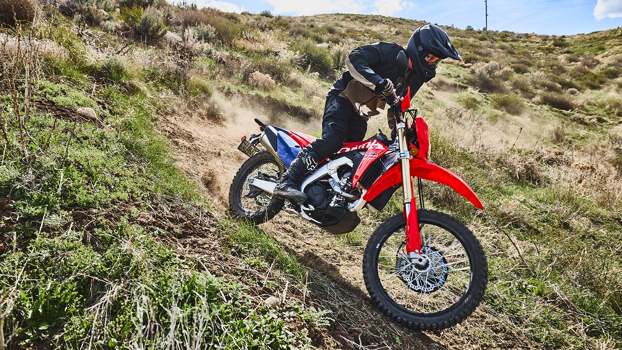 A rider on a dual sport motorcycle on a rugged trail.