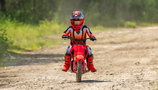 Vue latérale d'un jeune pilote négociant un virage sur terre avec la CRF50F.