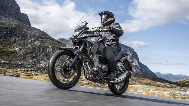 a rider wearing a helmet on a Honda motorcycle on the road in the mountains/ un pilote portant un casque sur une moto Honda sur la route dans les montagnes