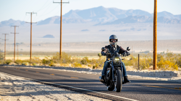 Un motard sur une moto roulant sur une autoroute du désert.  /  A biker on a motorcycle driving down a desert highway. 