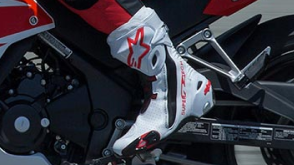 View of a biker feet wearing white motorcycle boots. / Vue des pieds d'un motard portant des bottes de moto blanches.