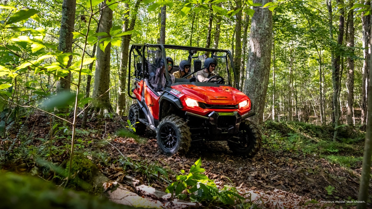Riders going around a corner in a Pioneer 1000 on a forest trail