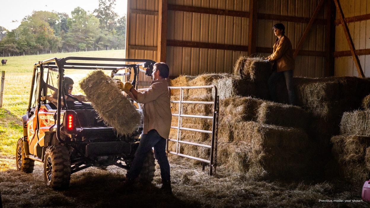 People loading hay into the back of a Pioneer 1000