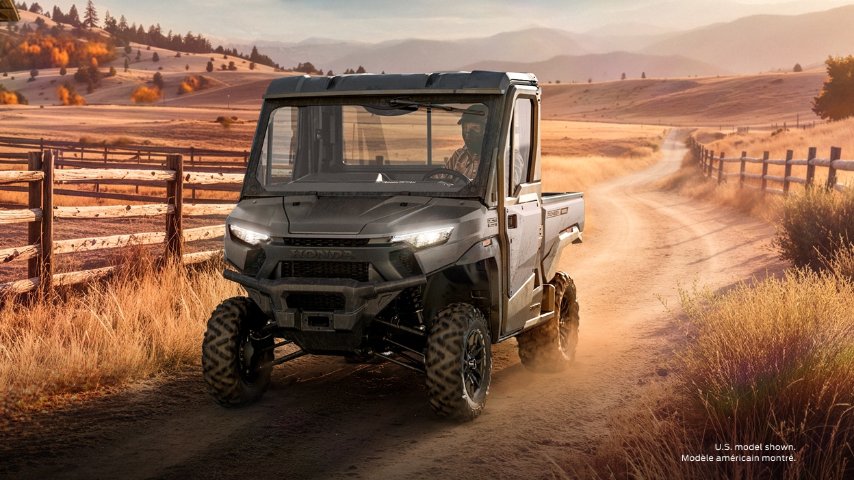 A grey Honda Pioneer 1000 Elite parked on a rural dirt road.