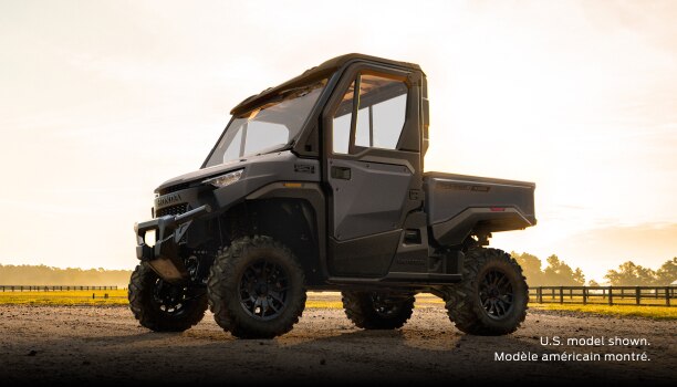 A grey Honda Pioneer 1000-3P Elite parked on a dirt road in a rural landscape.
