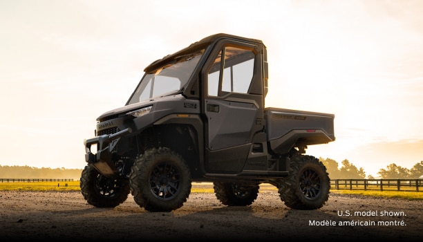 A grey Honda Pioneer 1000-3P Elite parked on a dirt road in a rural landscape.
