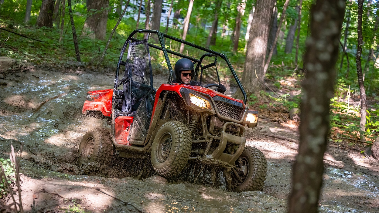 A Honda Pioneer 520 driving away on a trail.
