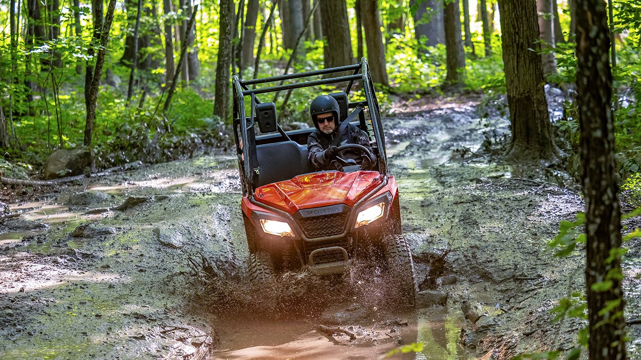A Honda Pioneer 520 splashing through water.
