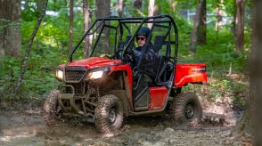 A Honda Pioneer 520 driving on a forest trail.