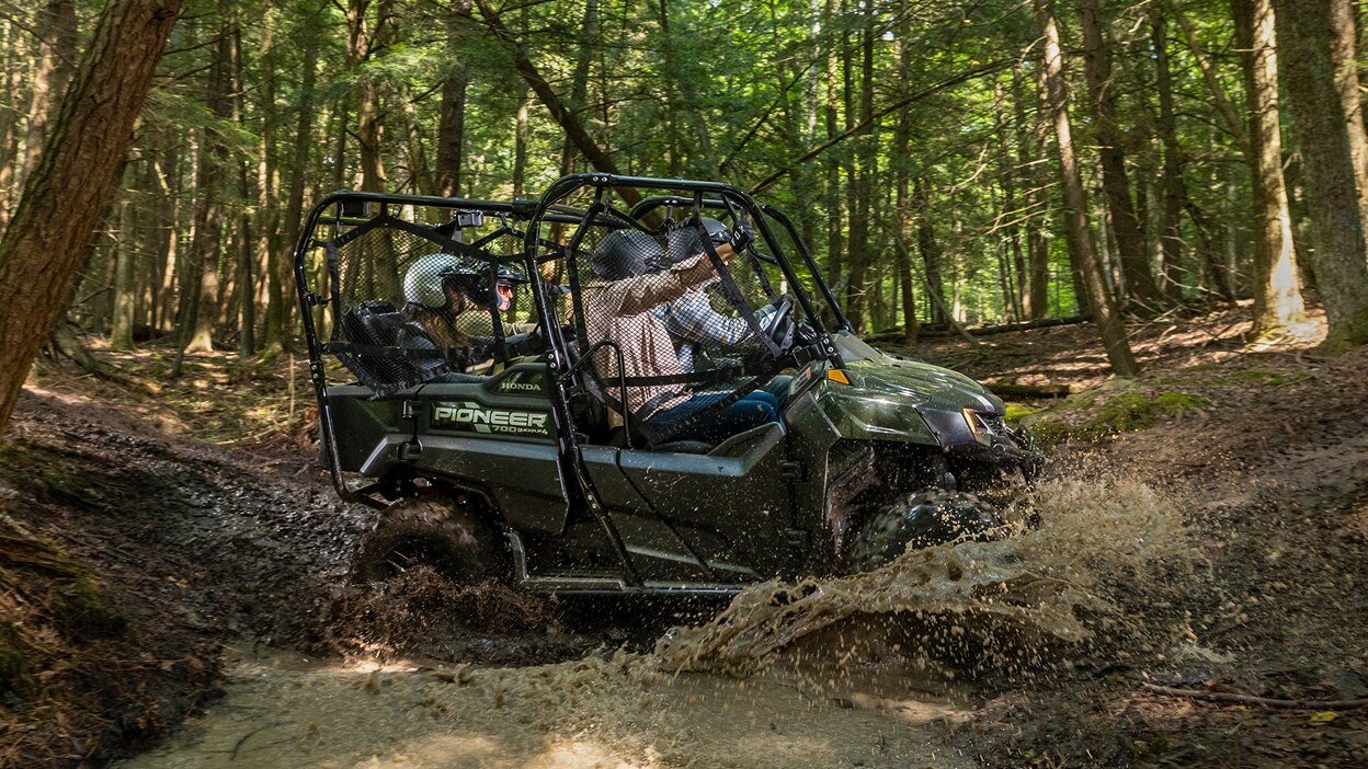 Small image of a green Honda Pioneer 700 on a muddy forest trail.