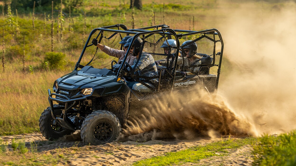 A Honda Pioneer 700 driving away on a dirt path.