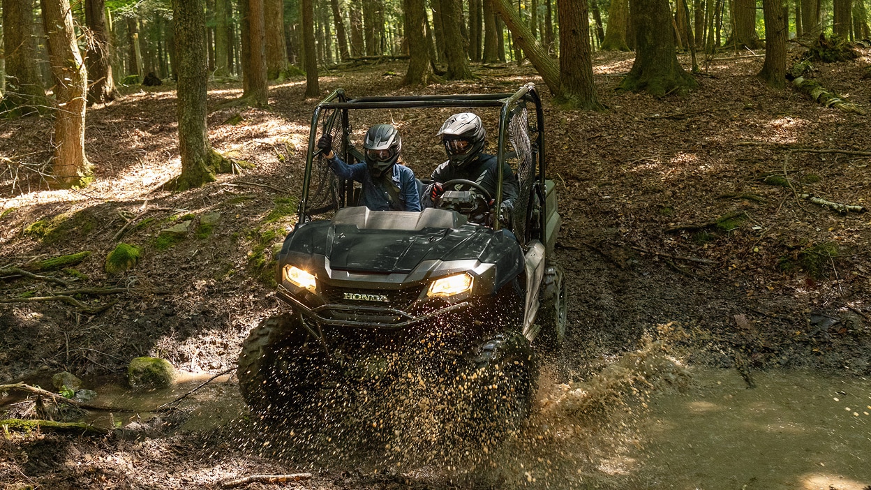 Un Honda Pioneer 700 sur un sentier de terre herbeux.