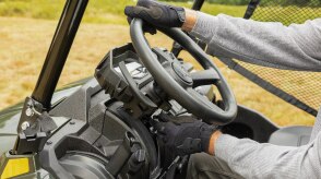 Close-up of a driver's hands gripping the steering wheel of a Honda Pioneer 700.